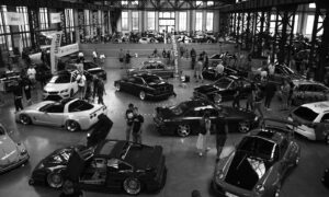 People gathered around custom cars at an indoor exhibition.