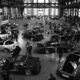 People gathered around custom cars at an indoor exhibition.