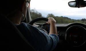 A woman drives a car down the road.