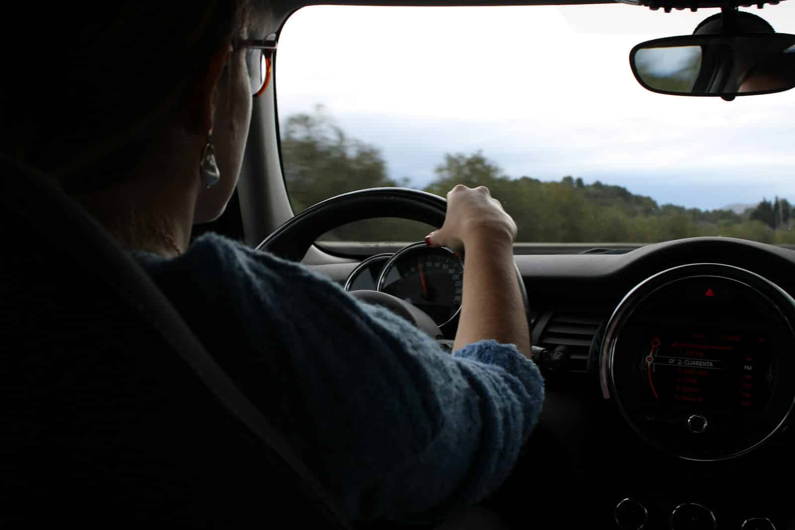 A woman drives a car down the road.