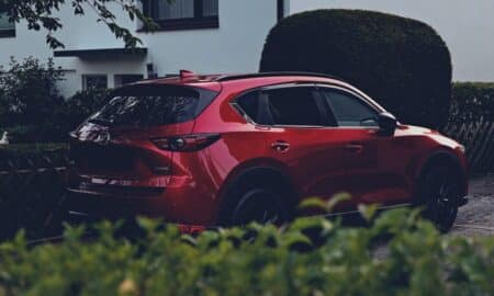 a red car parked in front of a hedge