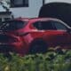 a red car parked in front of a hedge
