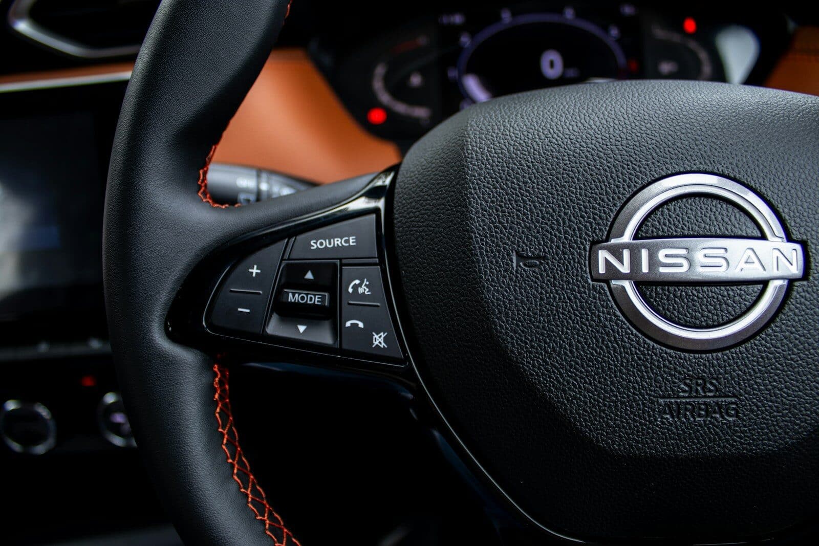 Close-up of a nissan steering wheel with controls.