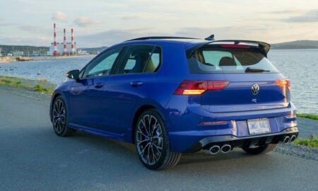 A blue car drives by the coast.