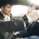 Man driving a car, gesturing with hand.