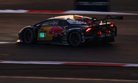 Race car with red bull livery speeds on track.