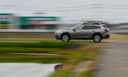 a car driving down a road next to a lush green field