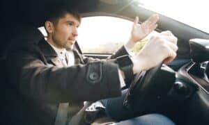 Man driving a car, gesturing with hand.