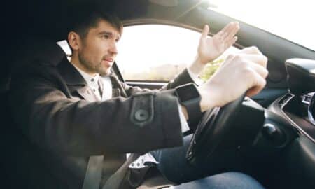 Man driving a car, gesturing with hand.