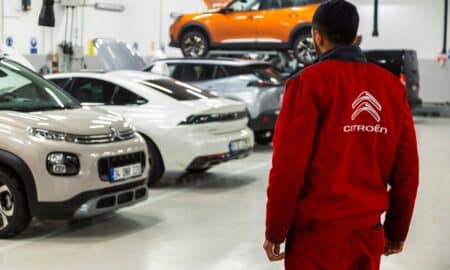 A man standing in a garage looking at cars