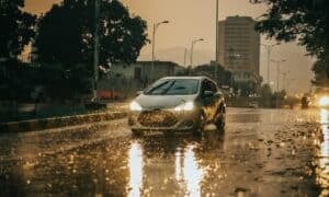 a car driving down a rain soaked street