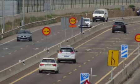 a large passenger jet flying over a busy highway