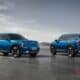 two blue suvs side by side in a parking lot