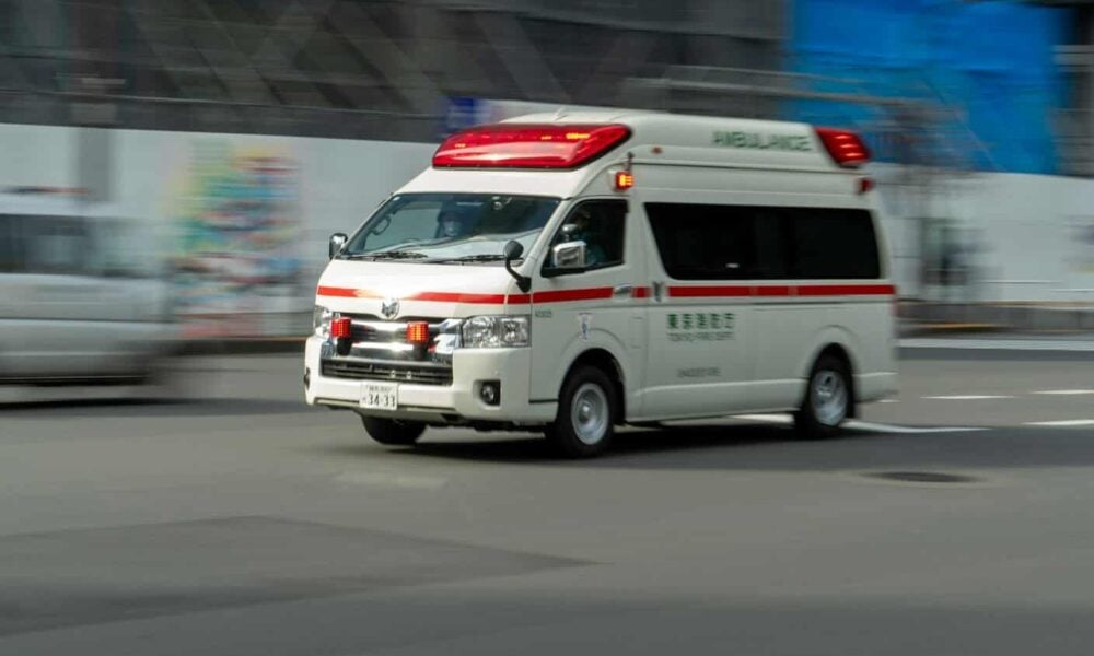 an ambulance driving down a street next to a building