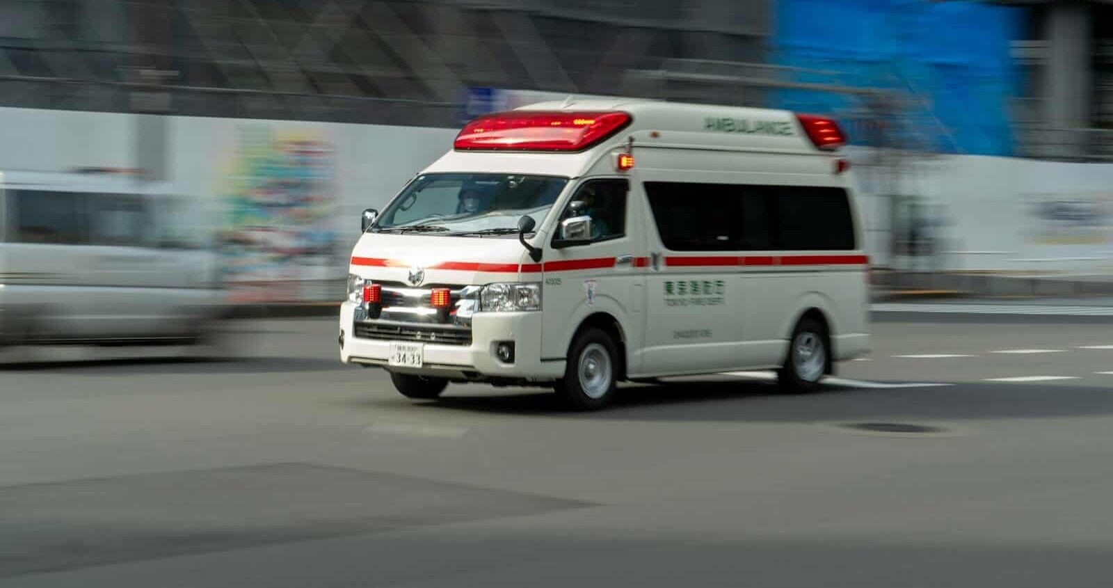 an ambulance driving down a street next to a building