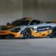 A grey and orange mclaren race car parked indoors