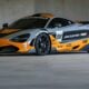 A grey and orange mclaren race car parked indoors