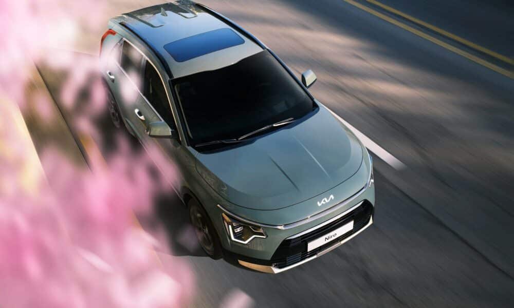 a silver car driving down a street next to pink flowers