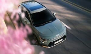a silver car driving down a street next to pink flowers