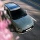 a silver car driving down a street next to pink flowers