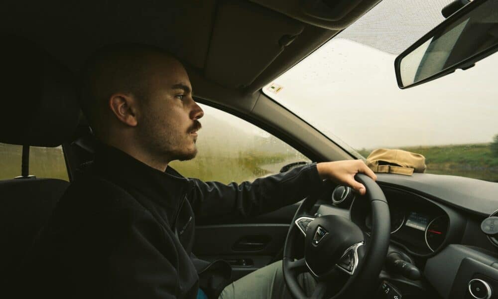 a man driving a car on a rural road