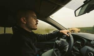a man driving a car on a rural road