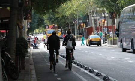 Two cyclists ride on a city street