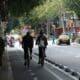 Two cyclists ride on a city street