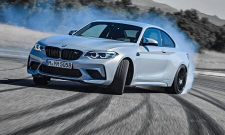 a white bmw car driving down a road