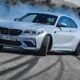 a white bmw car driving down a road