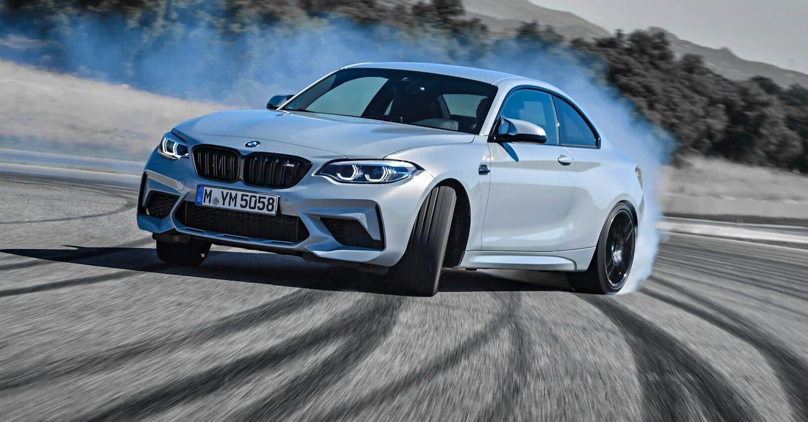 a white bmw car driving down a road